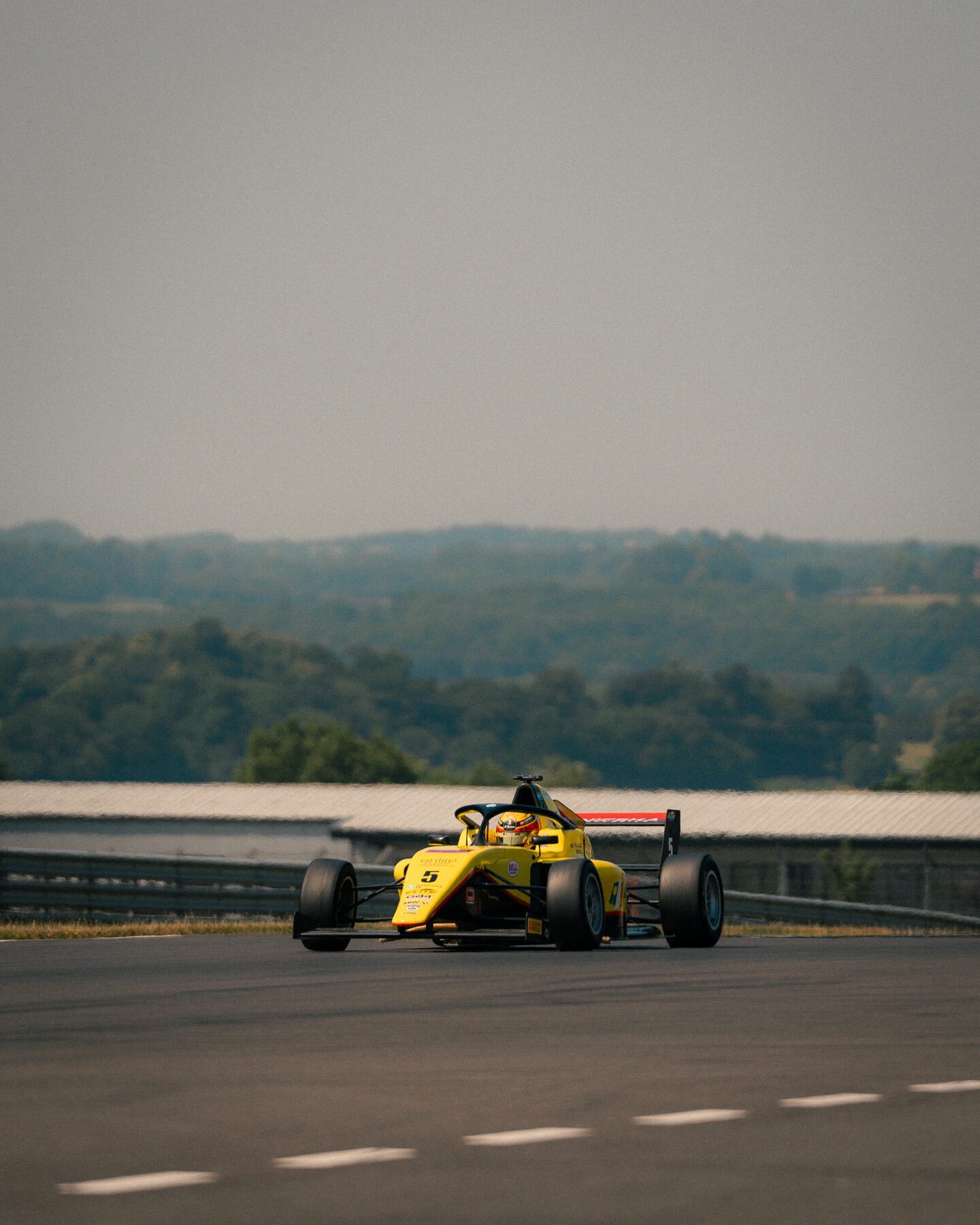 Formula car cornering on track under a hazy sky